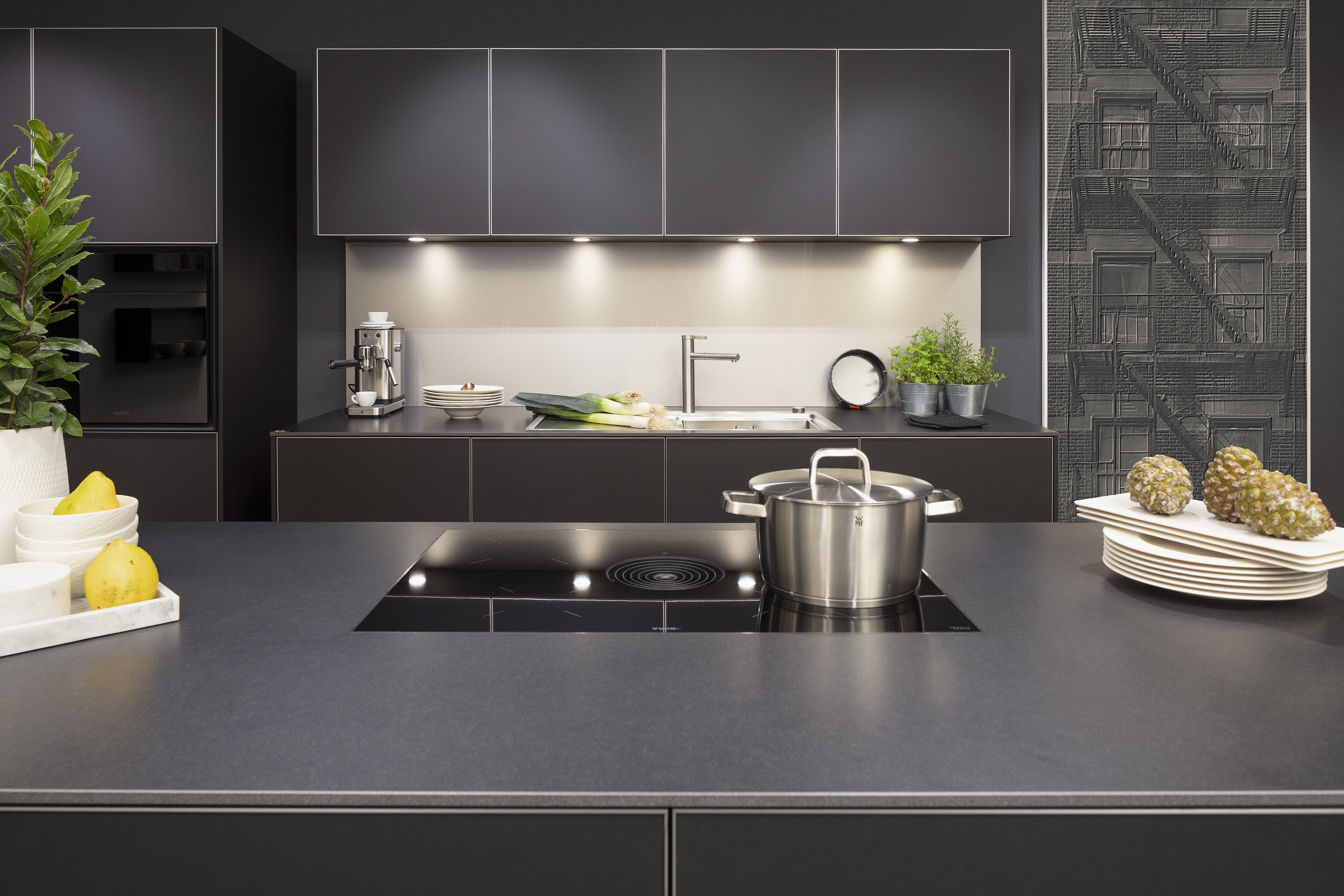 Front: Alu Tec RP Resopal Schwarz supermatt, Aluminiumkante APL: Schwarz Mikrostruktur  Geräte: Bora  Armatur und Spüle: Blanco  Features: stringentes Raster, Oberschränke quadratisch, Aluminiumkante, Regalsystem mit LED, Korpus Resopal Schwarz, Downlights, Schwarz/Edelstahl, Regale mit Edelstahlrückwand, Schubladen Holzfurnier. 