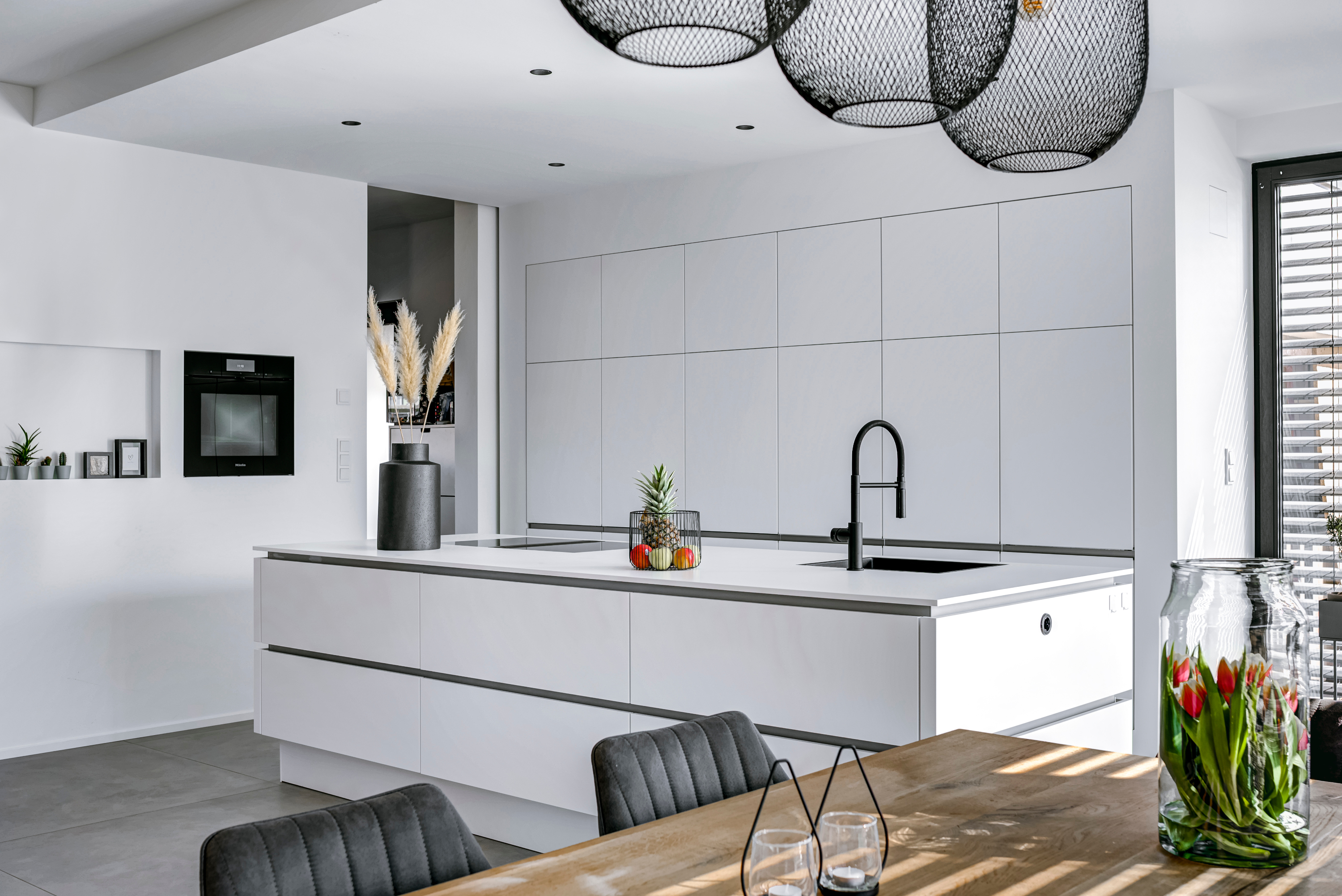 Moderne Küche weiß grifflos mit Kücheninsel und Esstisch im Vordergrund