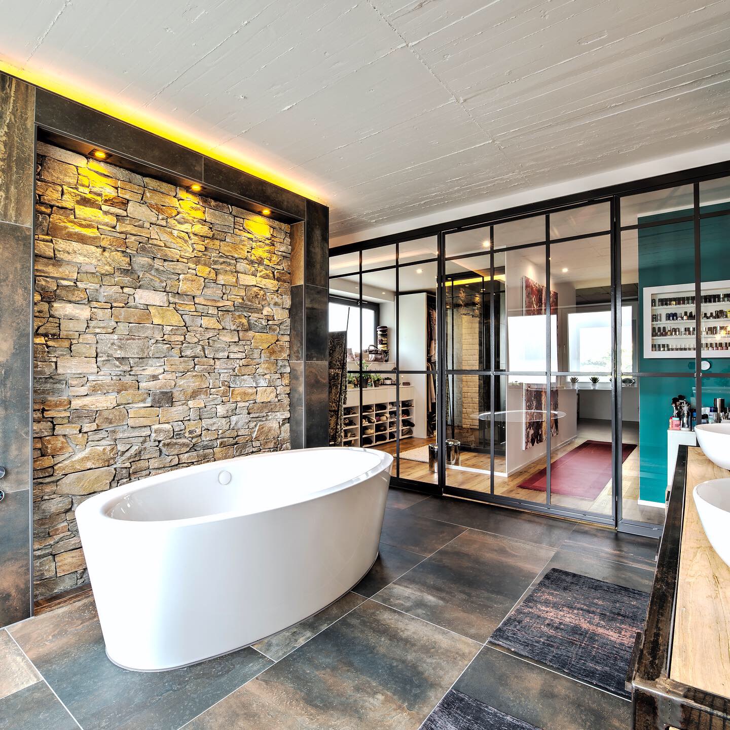 Modernes Badezimmer mit freistehender Badewanne vor Natursteinwand