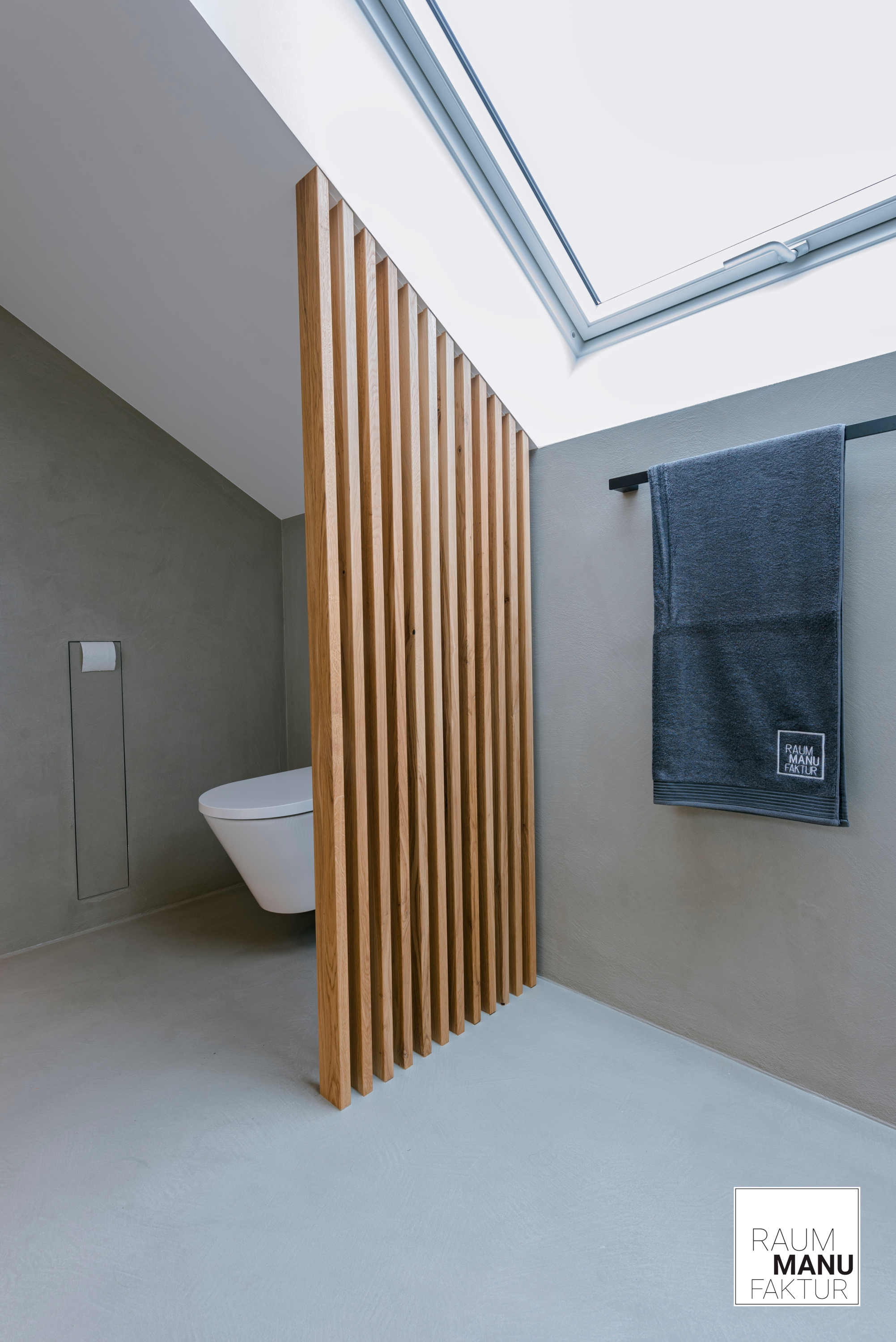 Modernes Badezimmer in Betonoptik mit Toilette hinter Holzpaneel