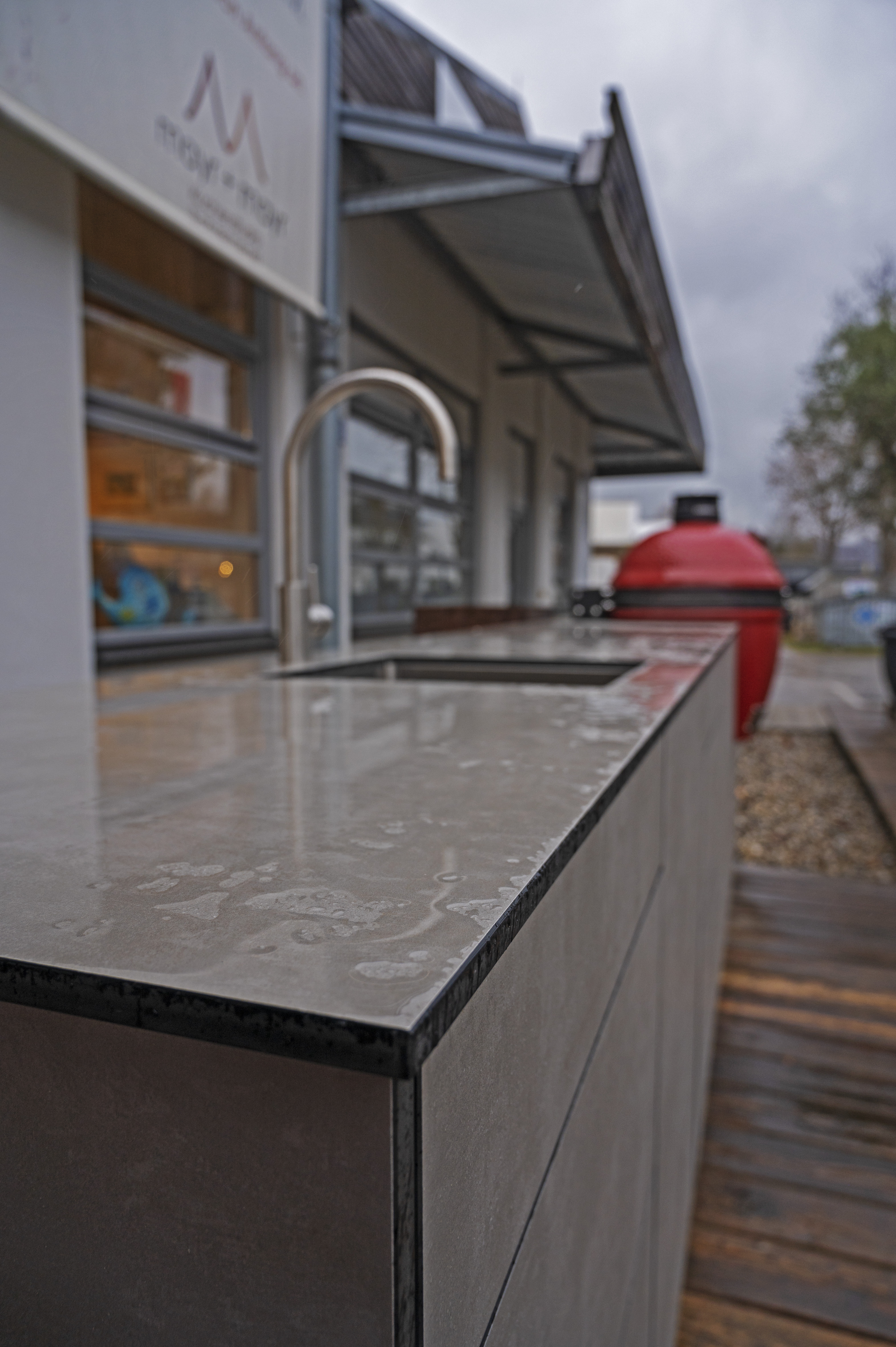 Regennässe auf Outdoor-Küche mit Hauswand und Terrasse im Hintergrund