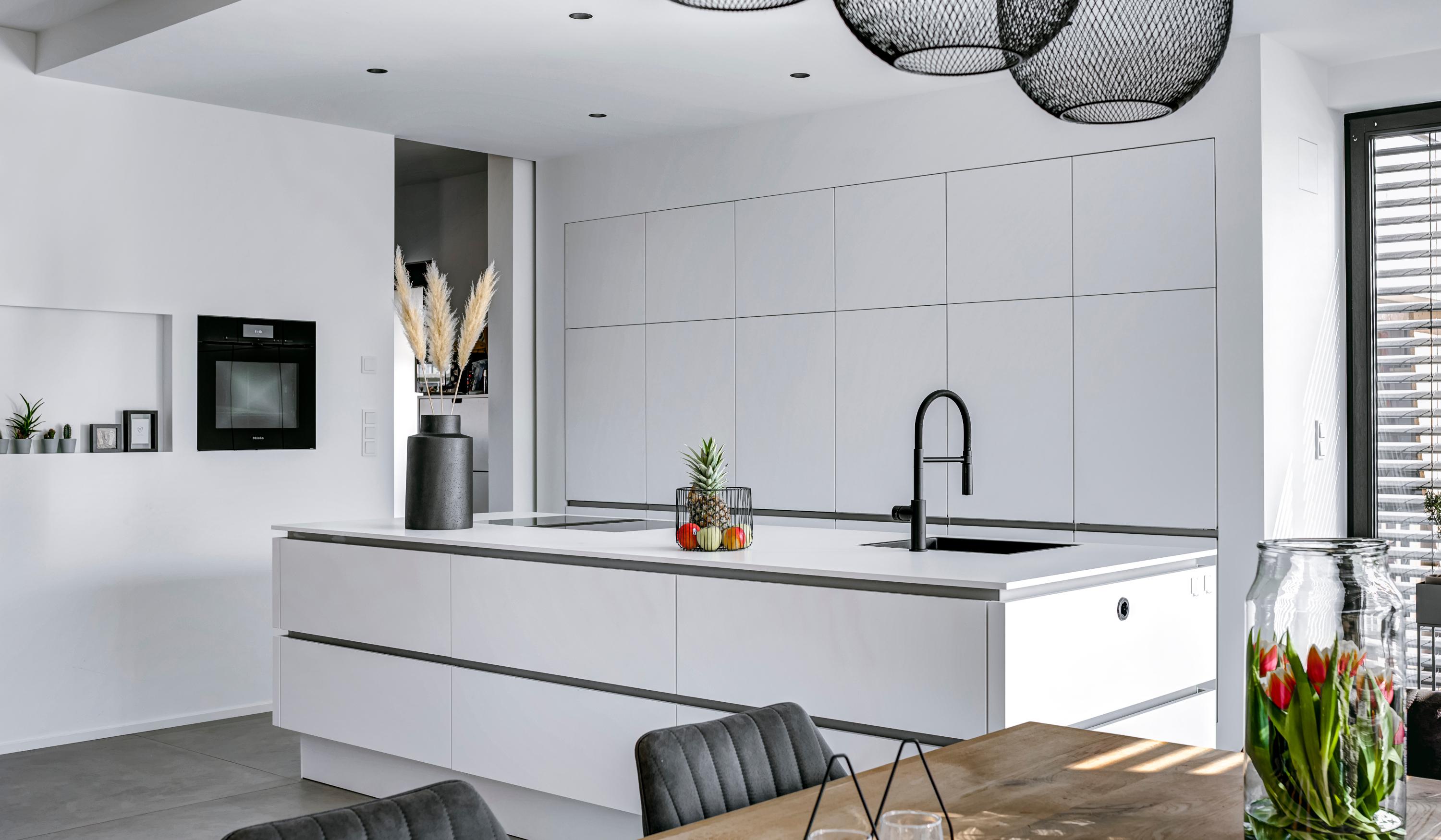 Moderne Küche weiß grifflos mit Kücheninsel und Esstisch im Vordergrund