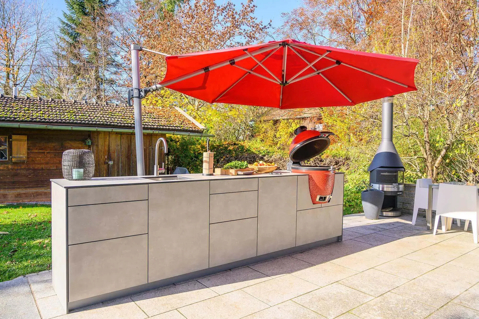Küchenzeile auf Terrasse unter rotem Sonnenschirm